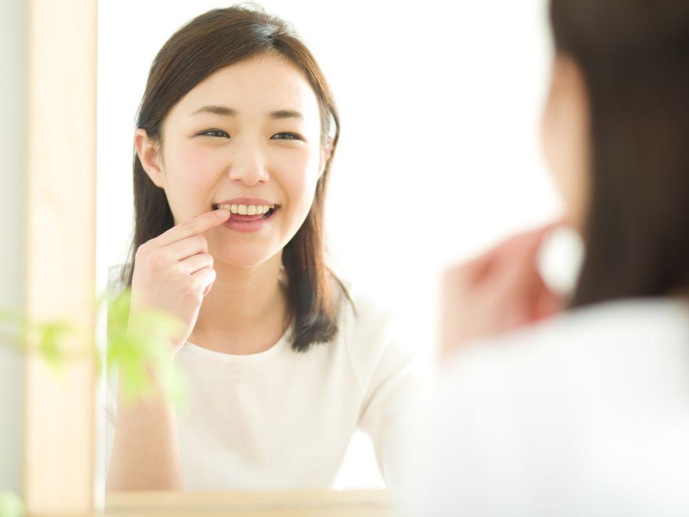 鏡を見て歯をチェックする女性