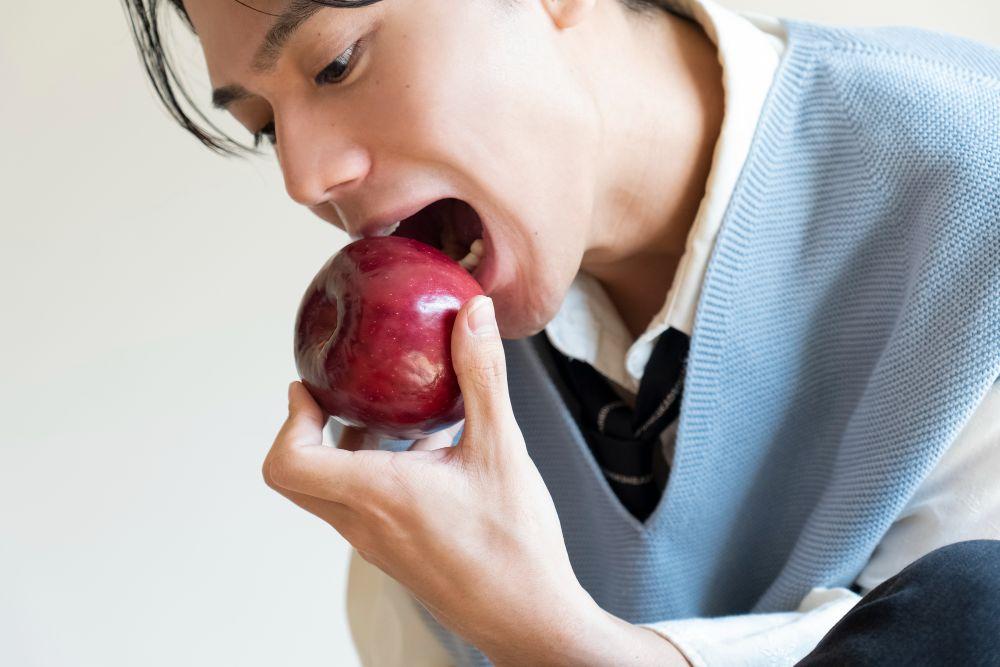 リンゴにかぶりつく男性